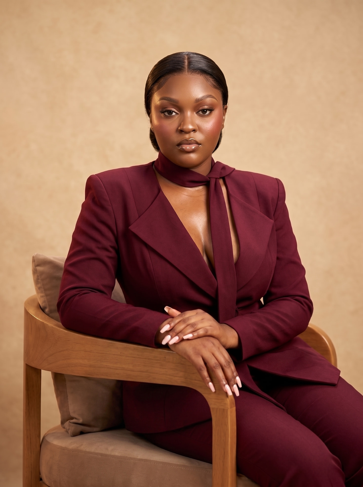 PurSole founder seated in a burgundy tailored suit against a warm beige backdrop